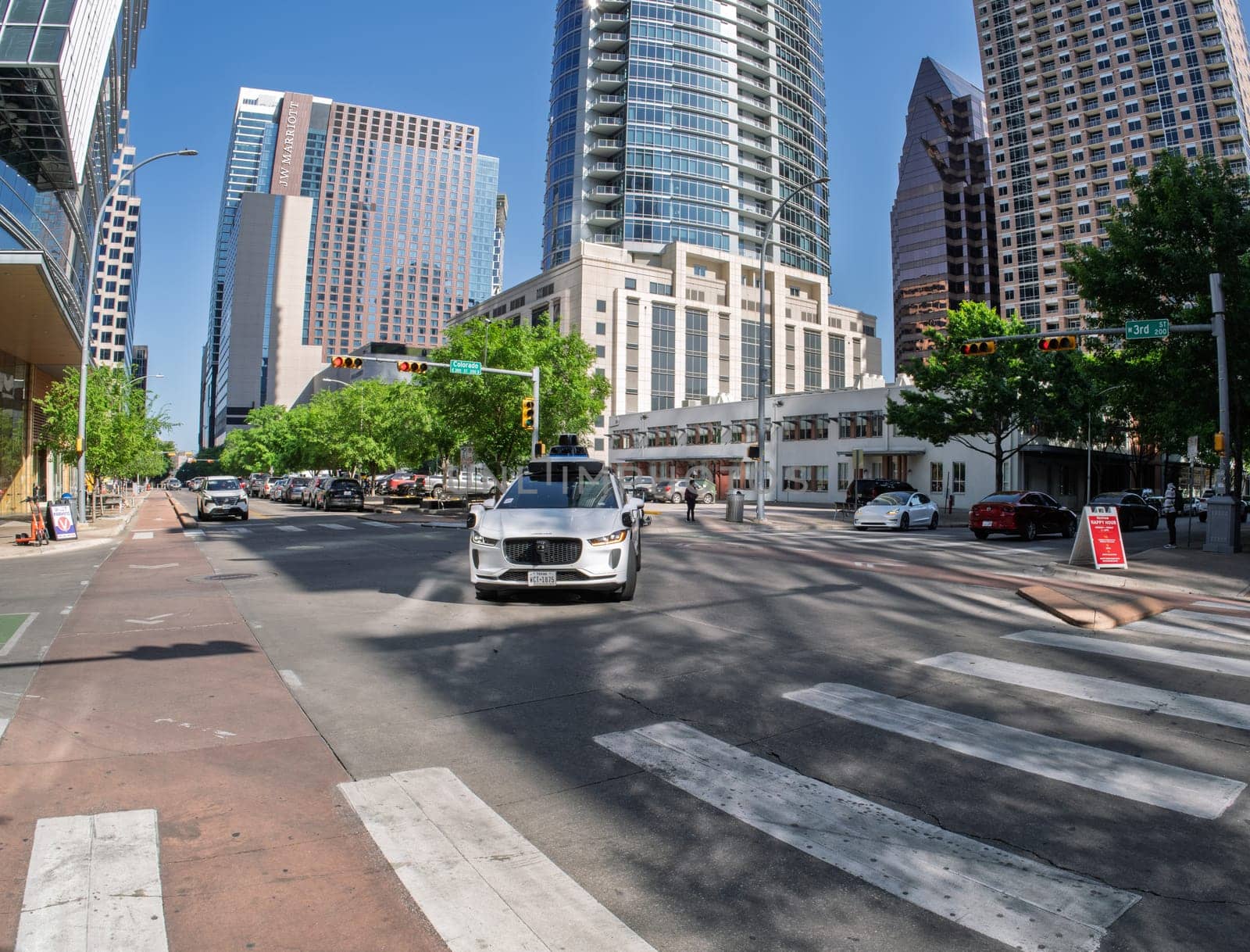 Austin, TX - 10 April 2025: Fisheye lens view of a Waymo Jaguar autonomous taxi turning at junction in downtown Austin, Texas