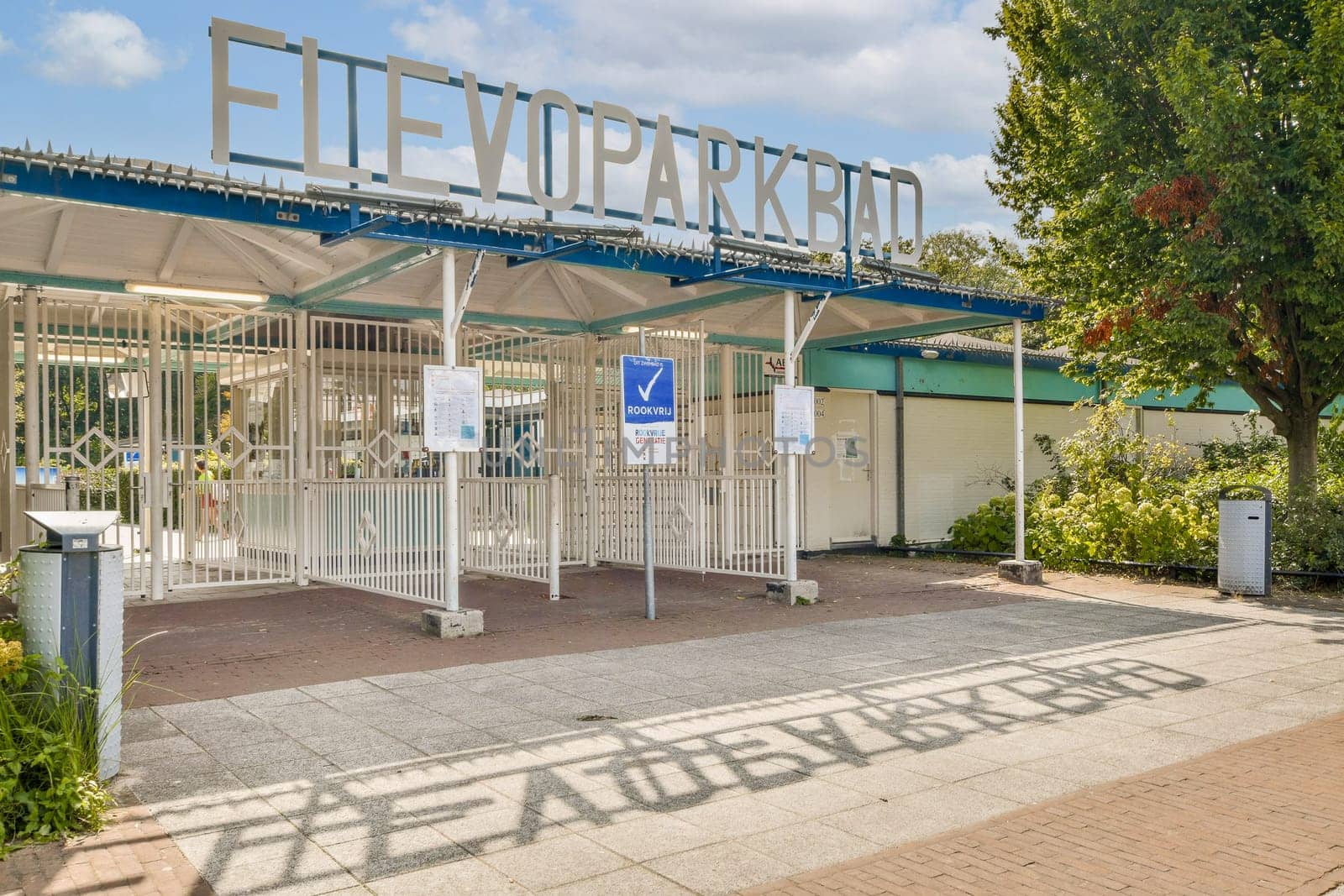 An inviting entrance gate showcases a park's name, surrounded by greenery and a well-maintained pathway, ready for visitors to explore.