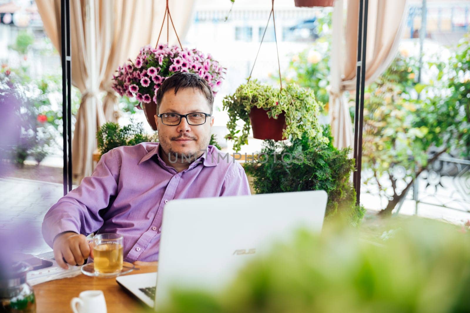 Man working on laptop online at table with food in restaurant
