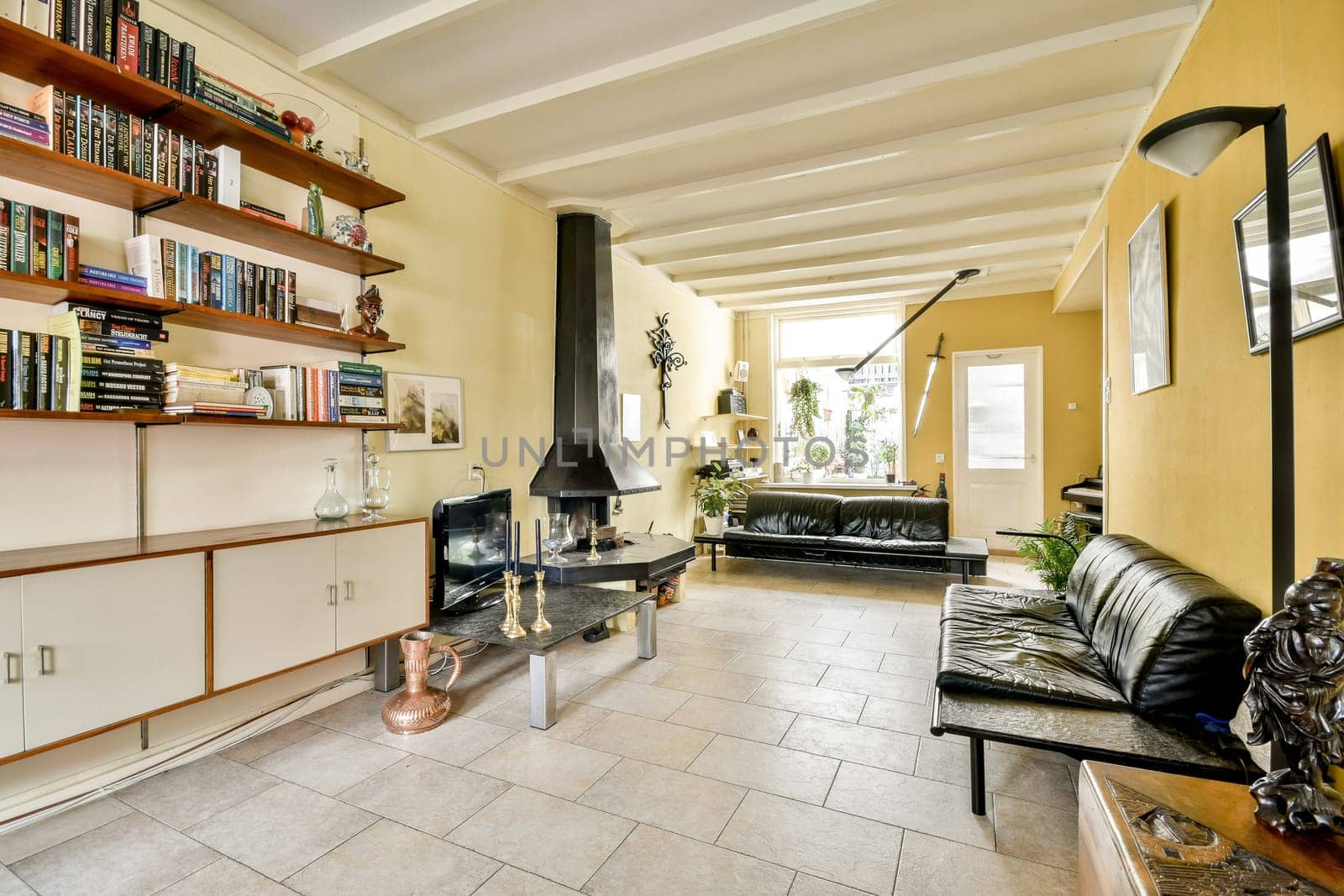 A stylish living room showcasing modern decor, featuring a sleek fireplace, comfortable seating, and shelves filled with books, creating a warm atmosphere.
