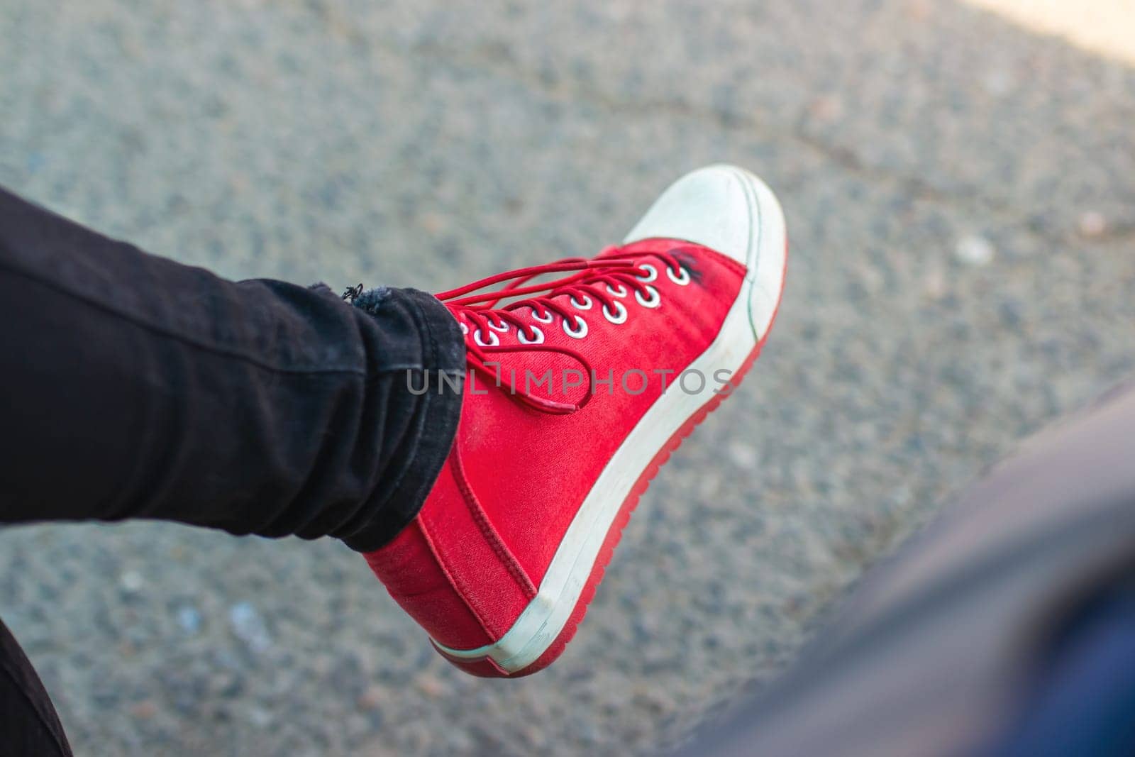 This image features a closeup view of a person s foot that is wearing stylish red sneakers, showcasing vibrant colors and fashionable design