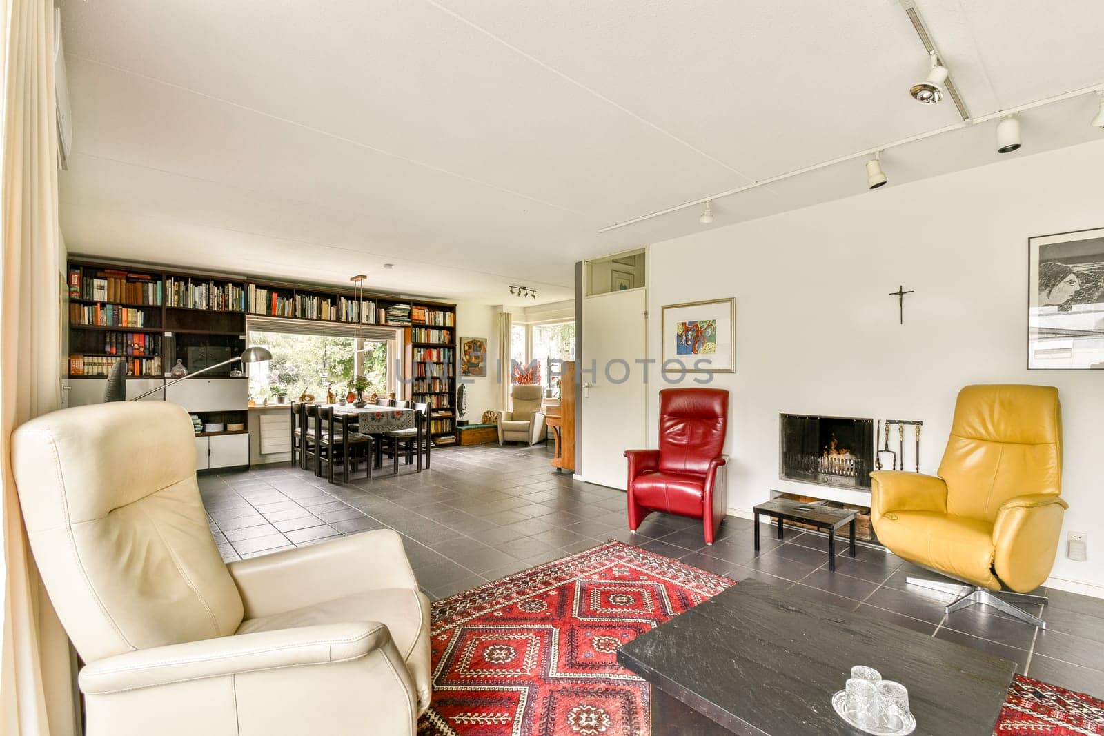 A spacious living room featuring elegant furniture, bookshelves, and vibrant decor, creating a warm and inviting atmosphere for relaxation.