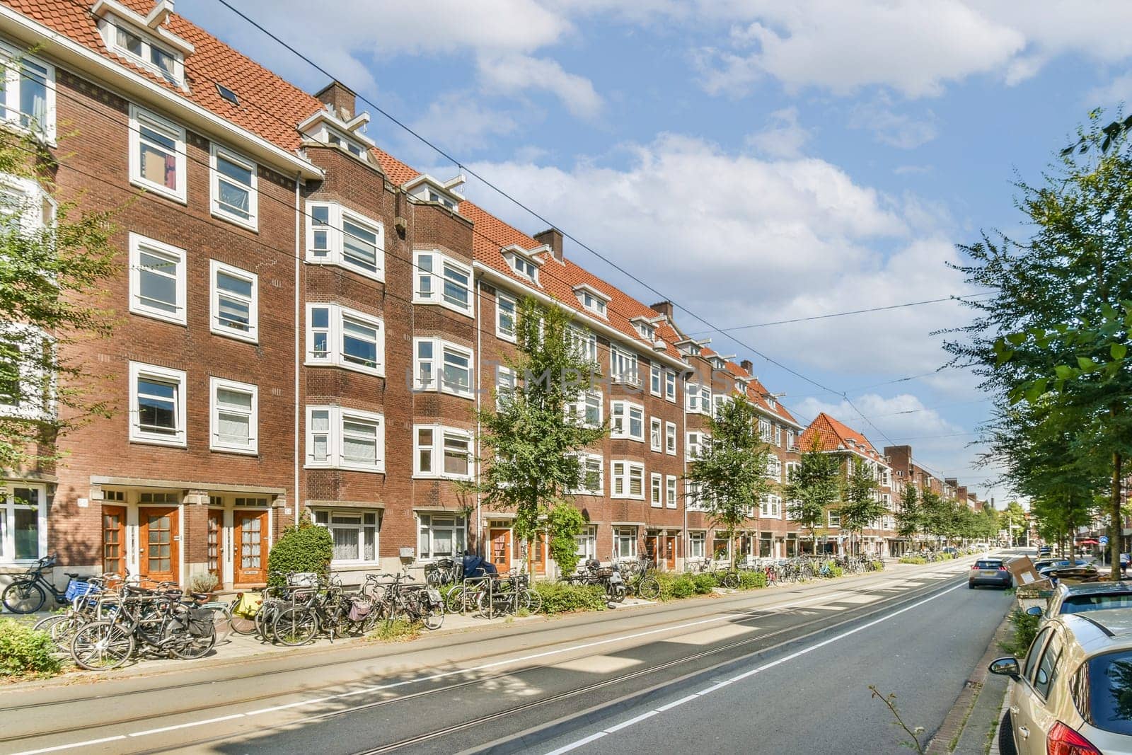 A picturesque urban street featuring charming historic buildings, lined with lush trees and parked bicycles, inviting a serene atmosphere for pedestrians.