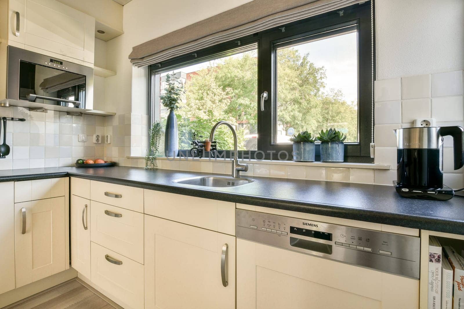 A sleek kitchen design featuring contemporary cabinetry, a view of greenery through the window, and stylish appliances for an inviting atmosphere.