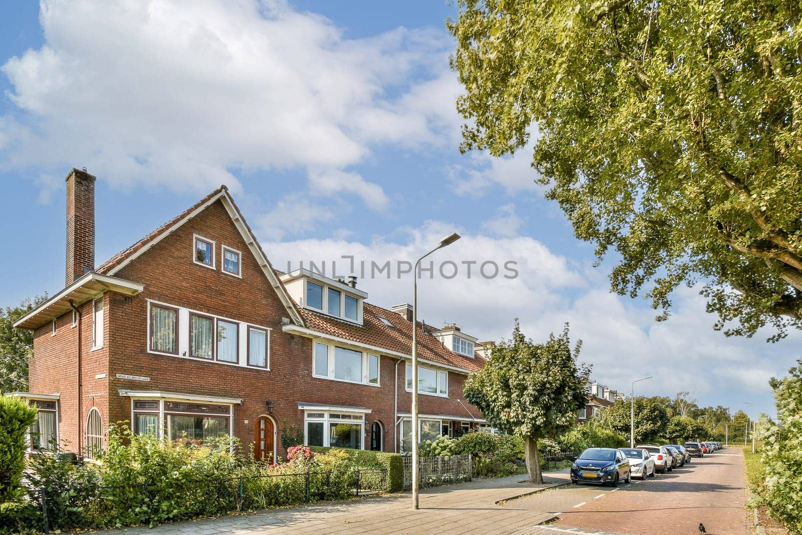 A picturesque scene featuring residential homes with red brick facades, lush greenery, and a clear blue sky, creating a serene and inviting atmosphere.
