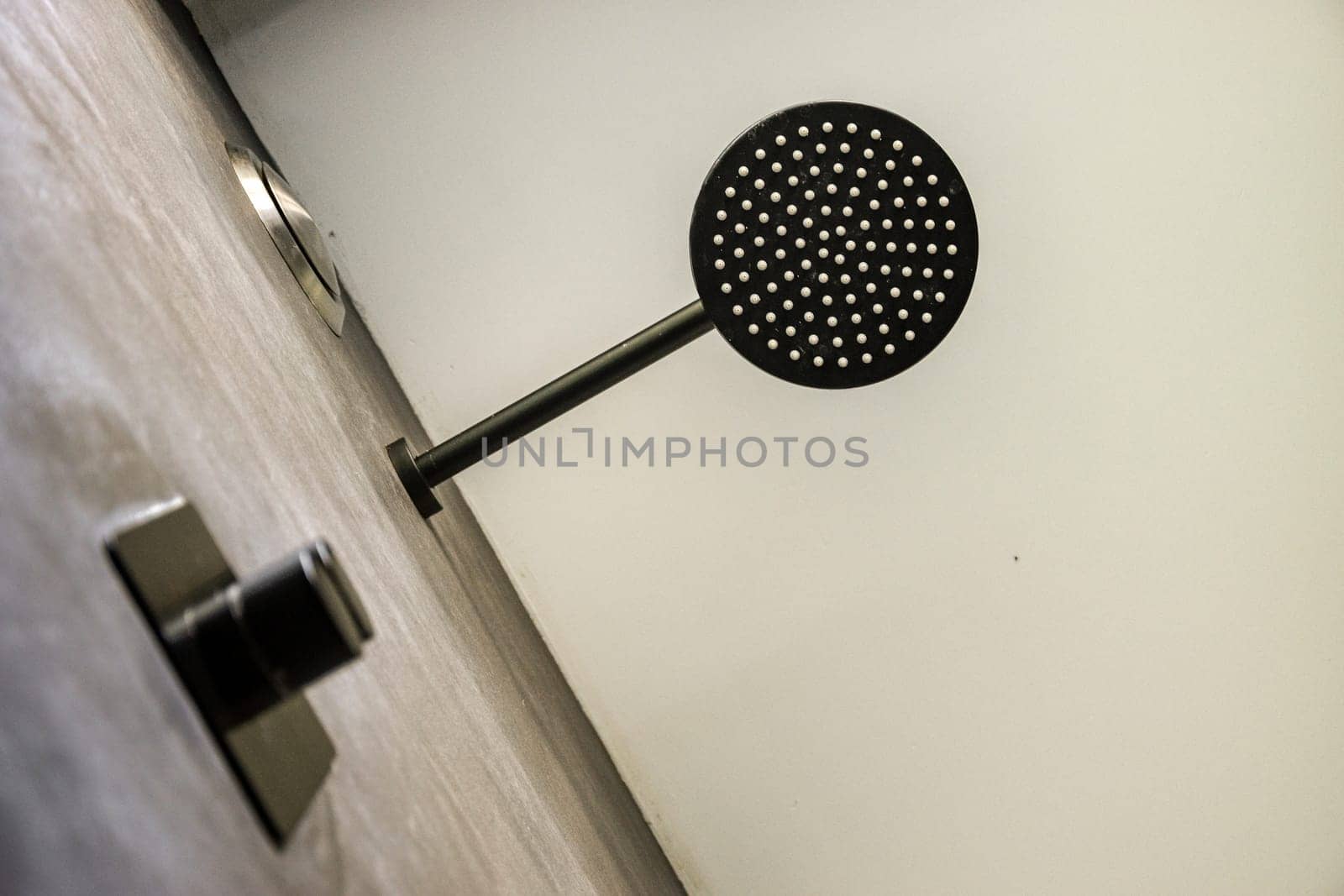 A sleek, modern shower head mounted in a minimalist bathroom setting features a unique design with a clean finish, emphasizing contemporary aesthetics.