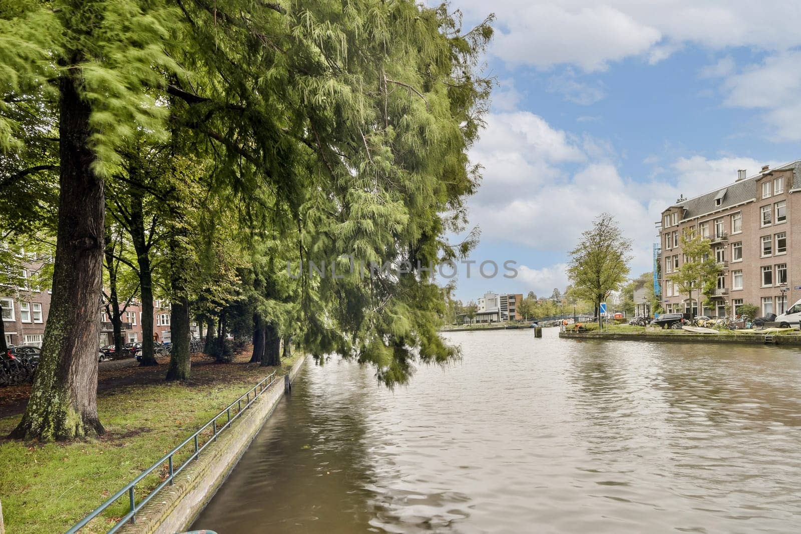 A beautiful view of a tranquil canal surrounded by vibrant greenery and charming architecture, perfect for a relaxing stroll or picturesque photography.