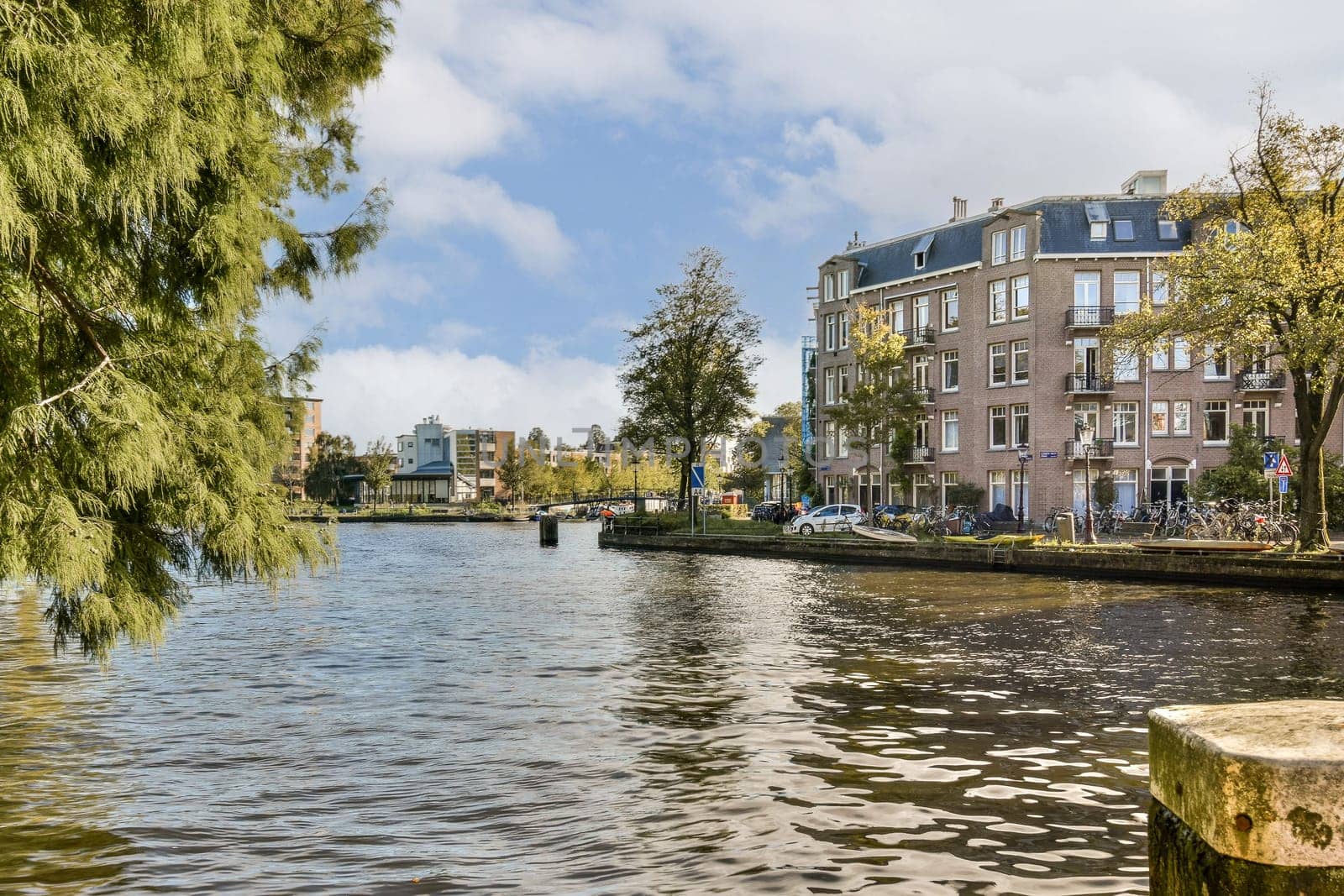 A peaceful canal scene surrounded by trees, showcasing historic buildings on one side and vibrant autumn colors reflecting in the water. Ideal for nature enthusiasts.