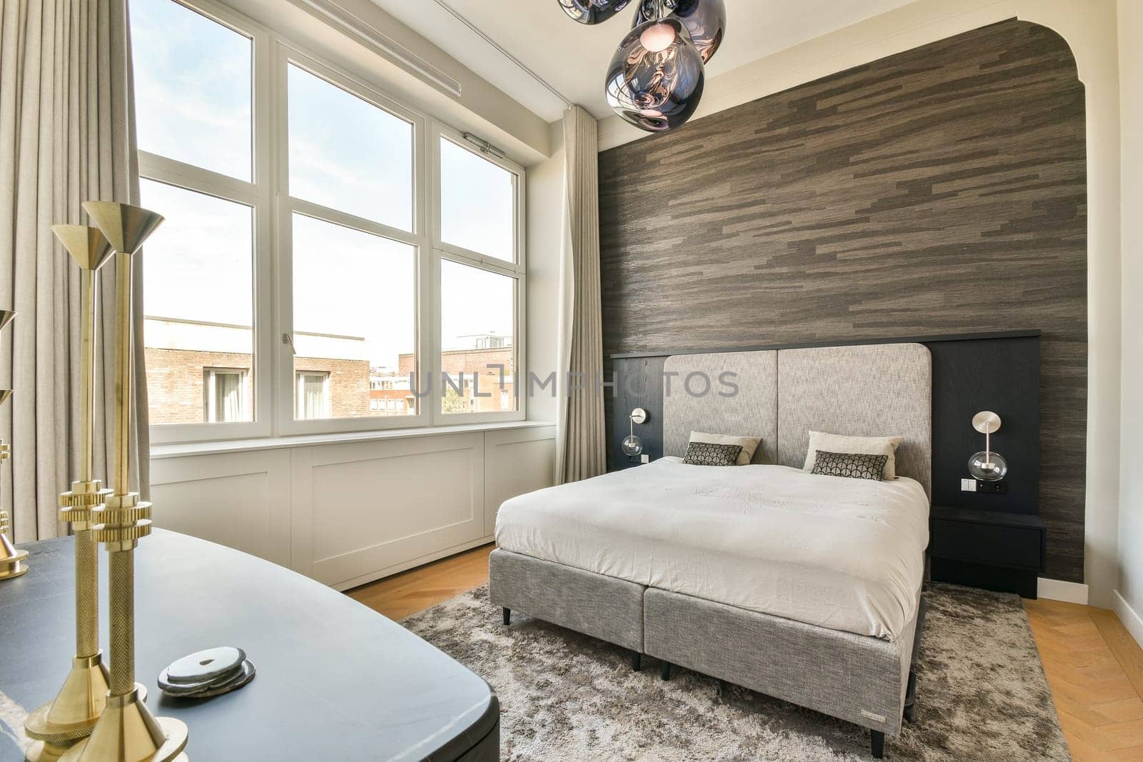 A stylish modern bedroom featuring large windows, a plush bed, elegant lighting, and a minimalist design that enhances natural light and spaciousness.