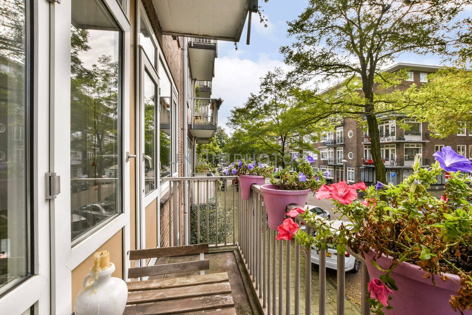 A vibrant urban balcony showcasing blooming flowers in colorful pots, surrounded by greenery and modern architecture, creating a lively outdoor space.
