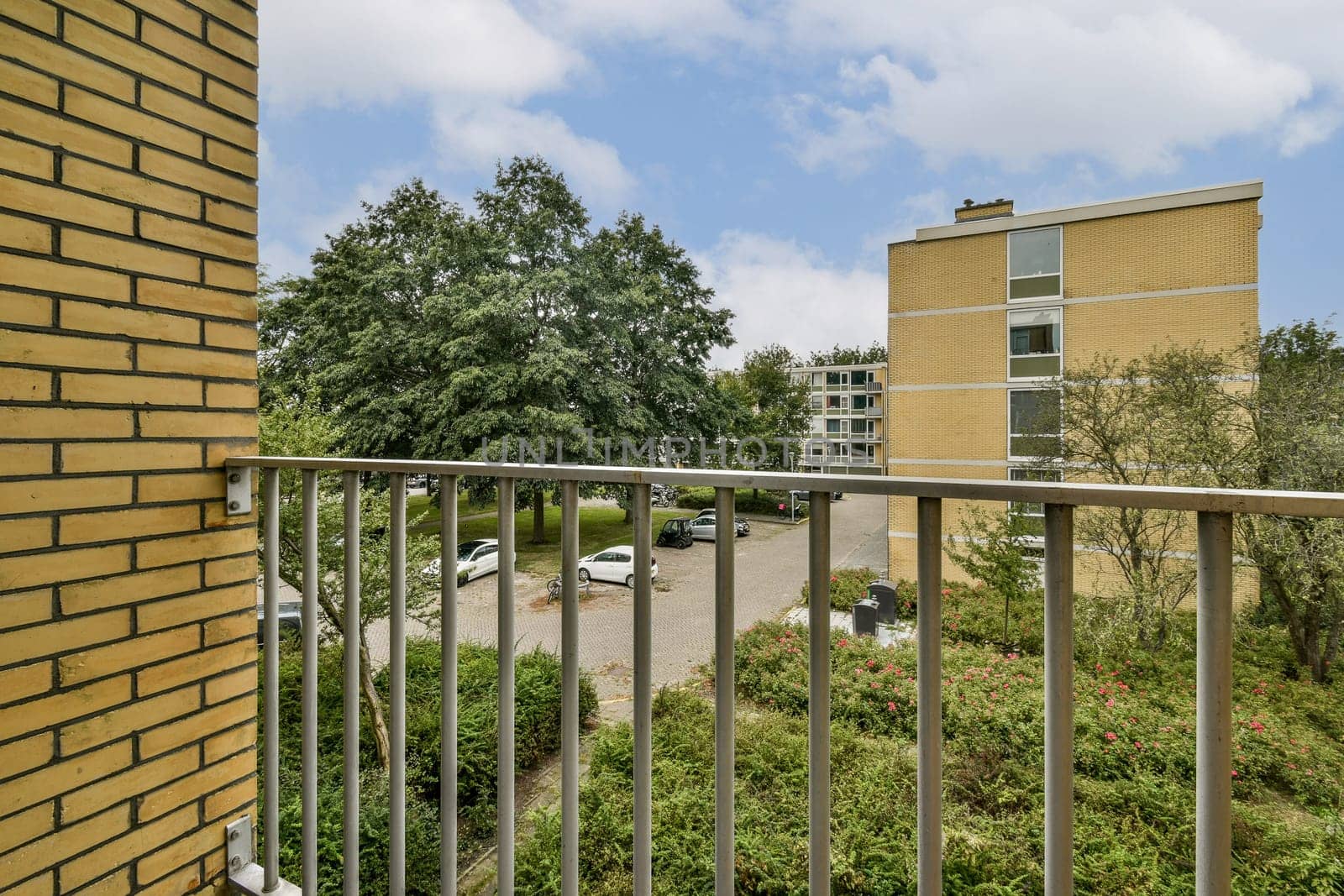 A picturesque view from a balcony showcasing greenery, residential buildings, and a peaceful environment, ideal for relaxation and enjoying nature.