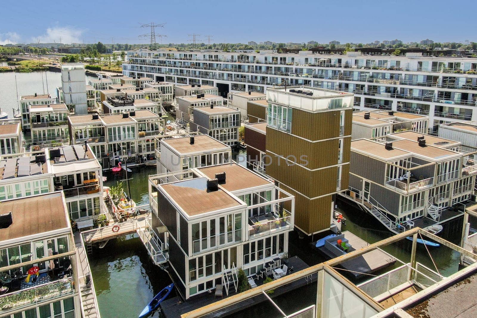 Aerial view of a contemporary housing development by the water showcasing stylish architecture surrounded by serene nature and vibrant community life.