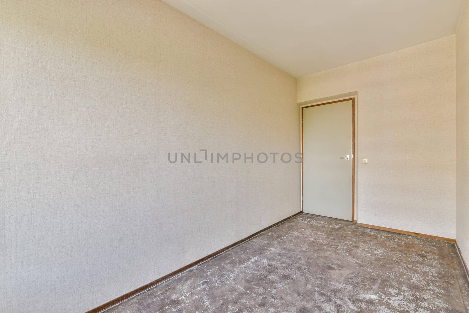 A minimalistic hallway featuring plain beige walls and a closed door, highlighting the absence of decorations or furnishings for an open, spacious feel.