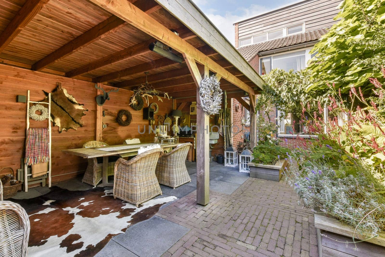 A beautifully arranged outdoor patio featuring wooden beams, natural decor, and a inviting dining area surrounded by lush greenery.