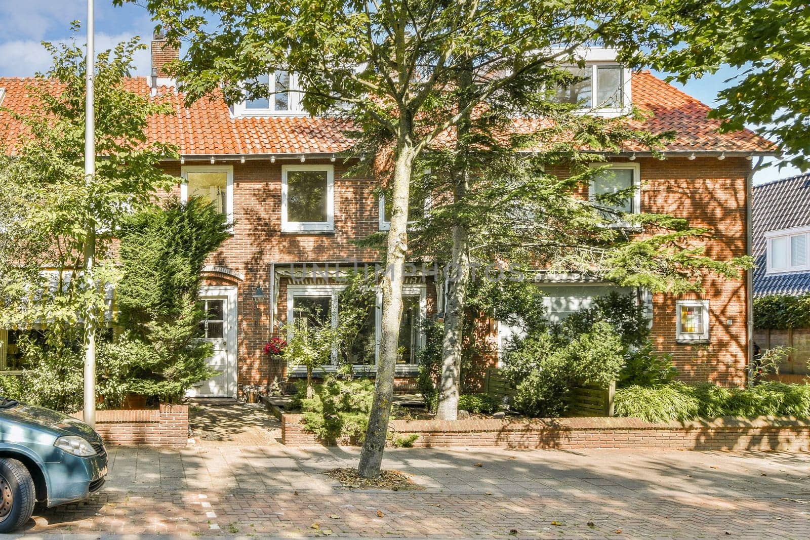 A picturesque suburban house with brick facade, lush trees, and well-kept garden, displaying a warm, inviting atmosphere in a serene setting.