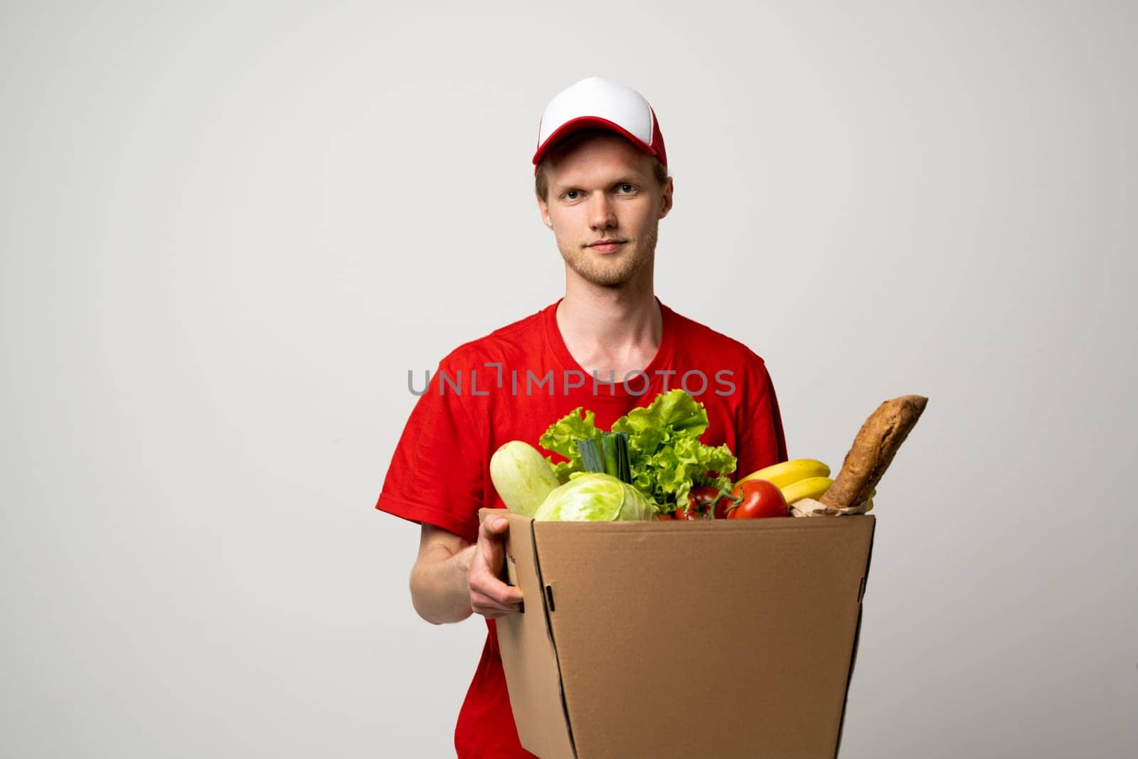 Deliver man wearing red uniform handling bag of food, fruit, vegetable. Postman and express grocery delivery service