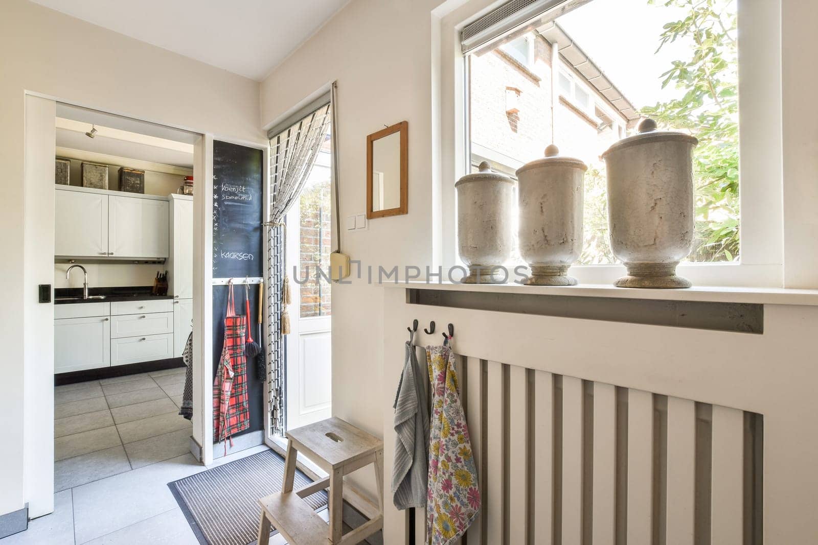 A fresh, inviting kitchen entryway with sleek design elements, showcasing contemporary fixtures, stylish decor, and natural light streaming in from windows.