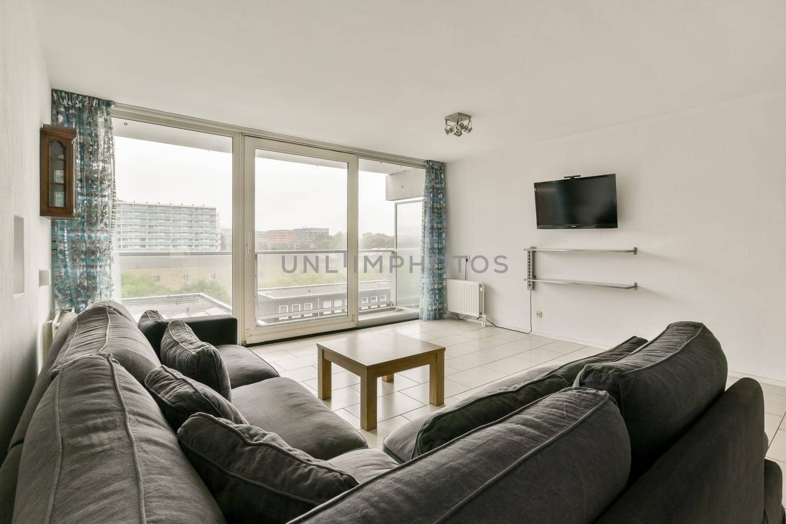 A stylish, contemporary living room featuring a cozy sofa, wooden coffee table, and large windows that offer an expansive view of the outside.