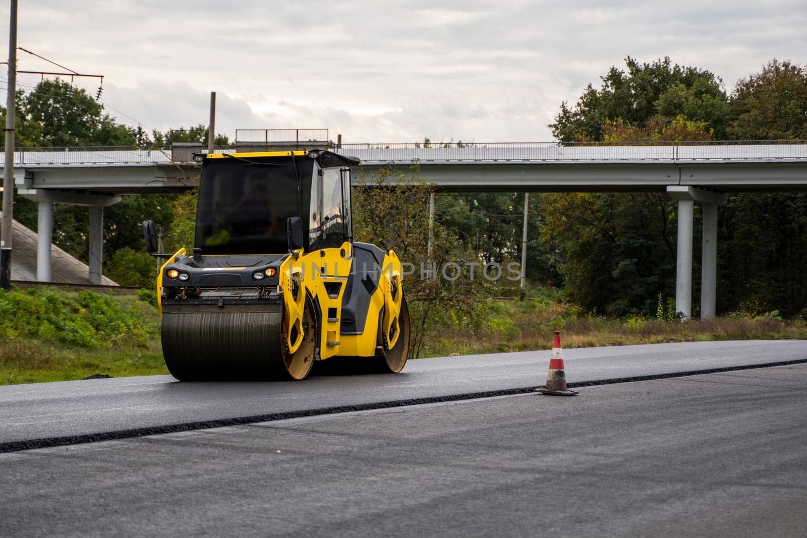 Heavy asphalt road roller with heavy vibration roller compactor that press new hot asphalt on the roadway on a road construction site on a street