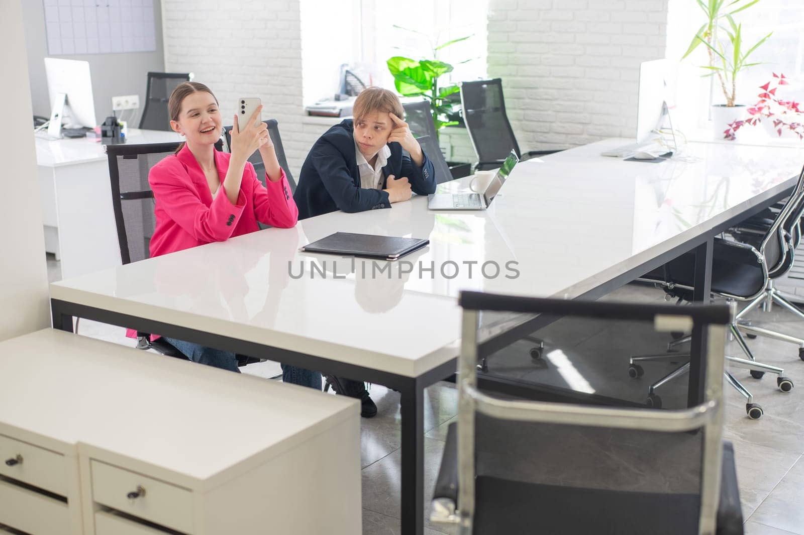 Caucasian Businesswoman Uses Smartphone While Colleague Has Problems At Work