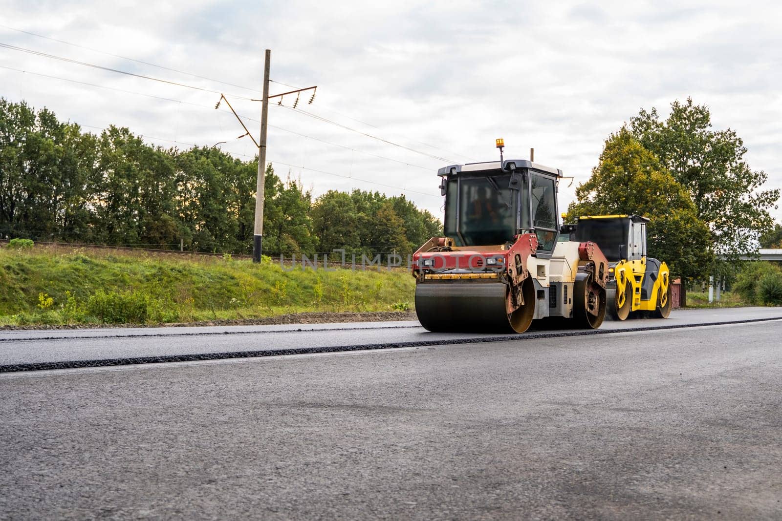 Two Heavy Asphalt Road Roller with heavy vibration roller compactor that press new hot asphalt on the roadway on a road construction