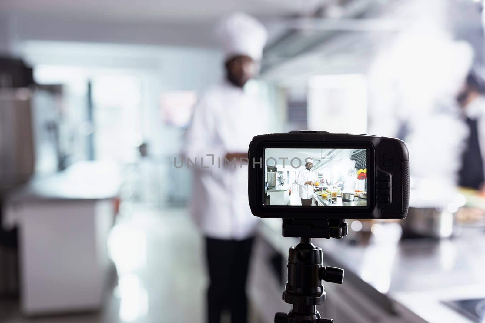 African american chef teaches his audience cooking skills on a video, explaining preparation methods and plating techniques. Expert hosting virtual classroom for online culinary training.