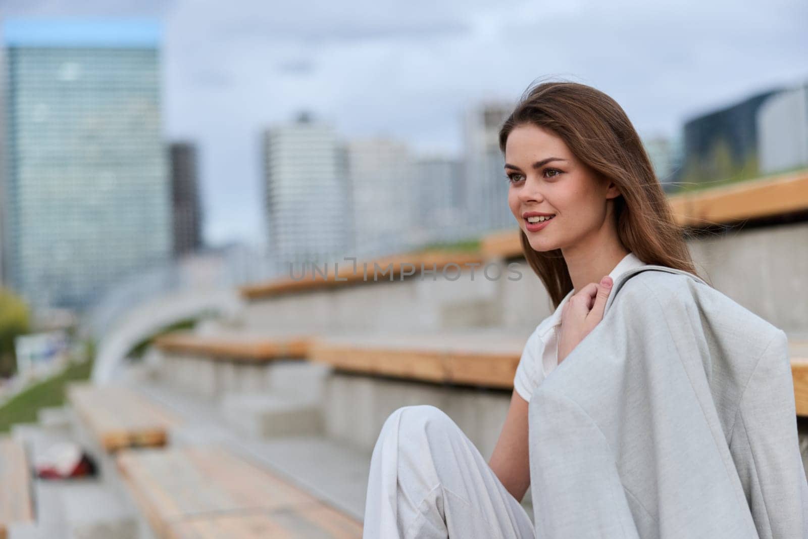A stylish woman dressed in business attire smiles confidently in an urban setting, reflecting empowerment, professionalism, and modern fashion in a contemporary cityscape.