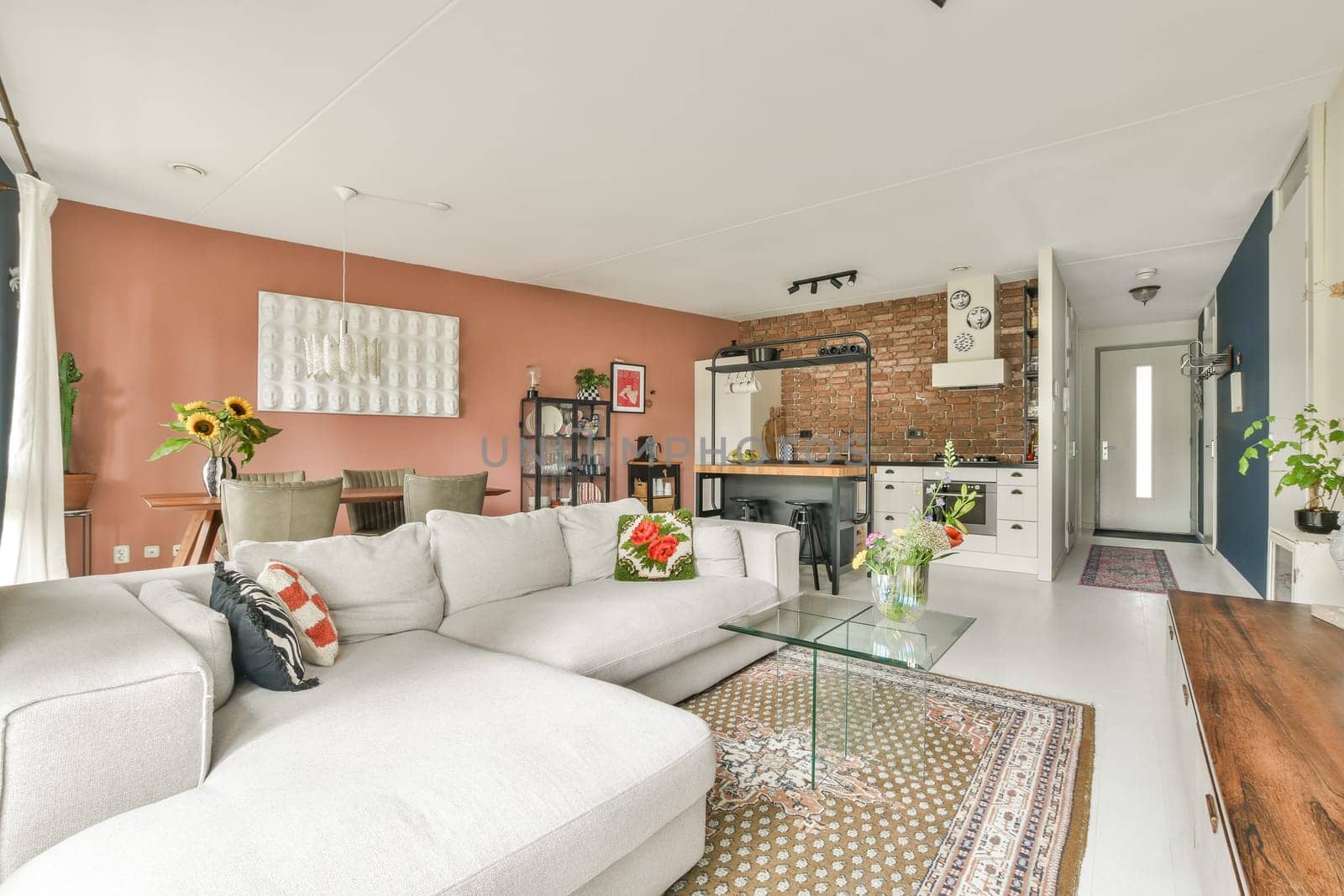 A chic modern living room featuring a comfortable sofa, vibrant decor, and an open kitchen design, creating a warm and inviting atmosphere for relaxation.