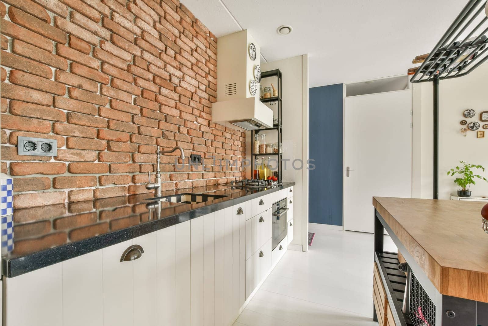 A stylish modern kitchen featuring exposed brick walls, sleek cabinetry, and minimalistic decor. The design offers a blend of rustic and contemporary aesthetics.