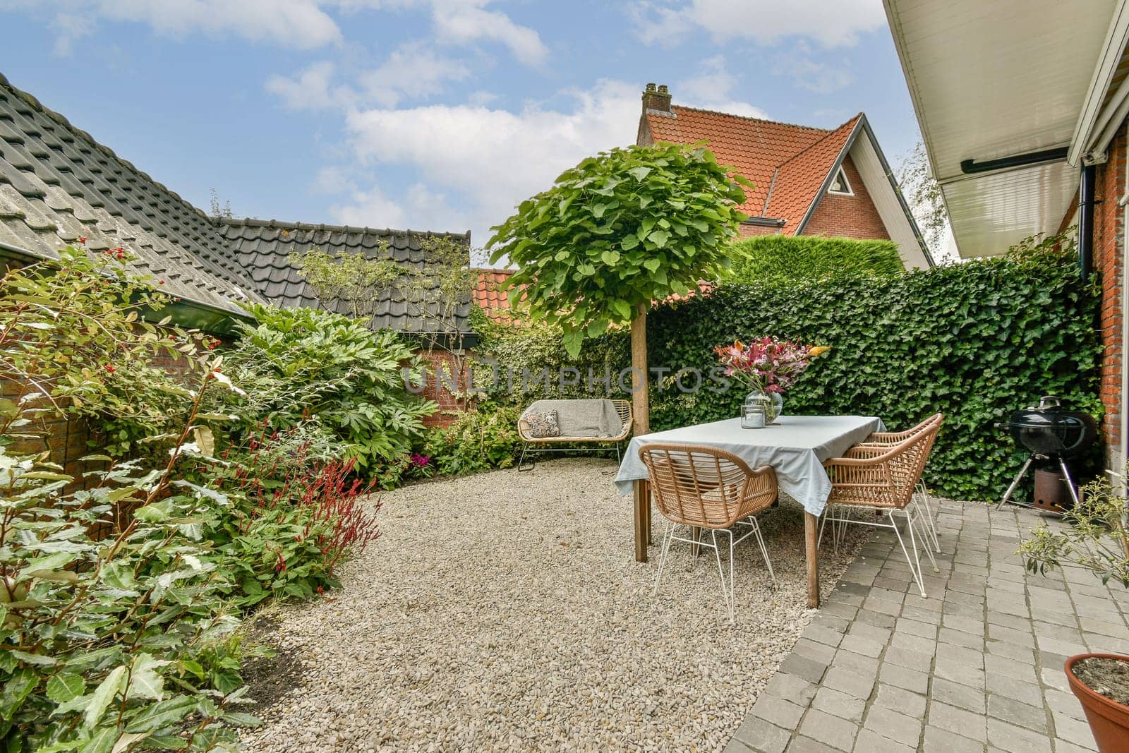 A serene garden patio featuring a cozy seating area, lush green plants, and a delightful arrangement of flowers, perfect for relaxation and outdoor gatherings.