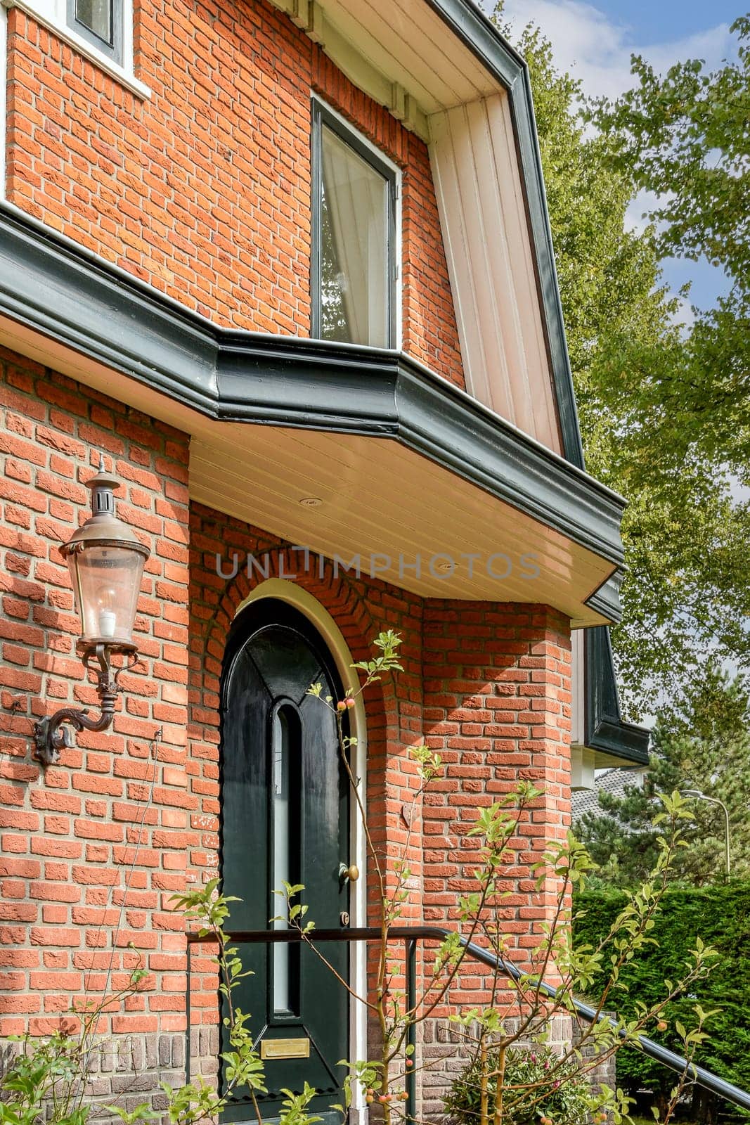 A picturesque brick home showcasing elegant architecture, complemented by lush bushes and trees in the surrounding garden.