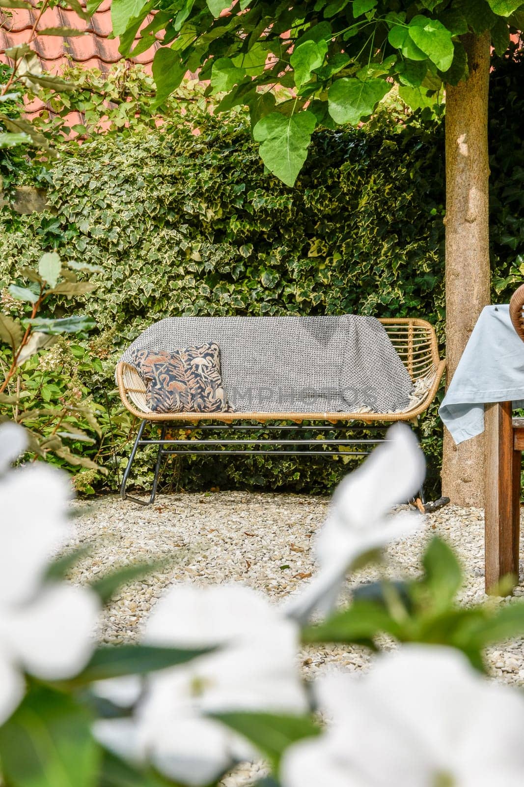 A tranquil garden scene featuring a comfortable seating area surrounded by lush greenery and vibrant flowers, perfect for relaxation or socializing.