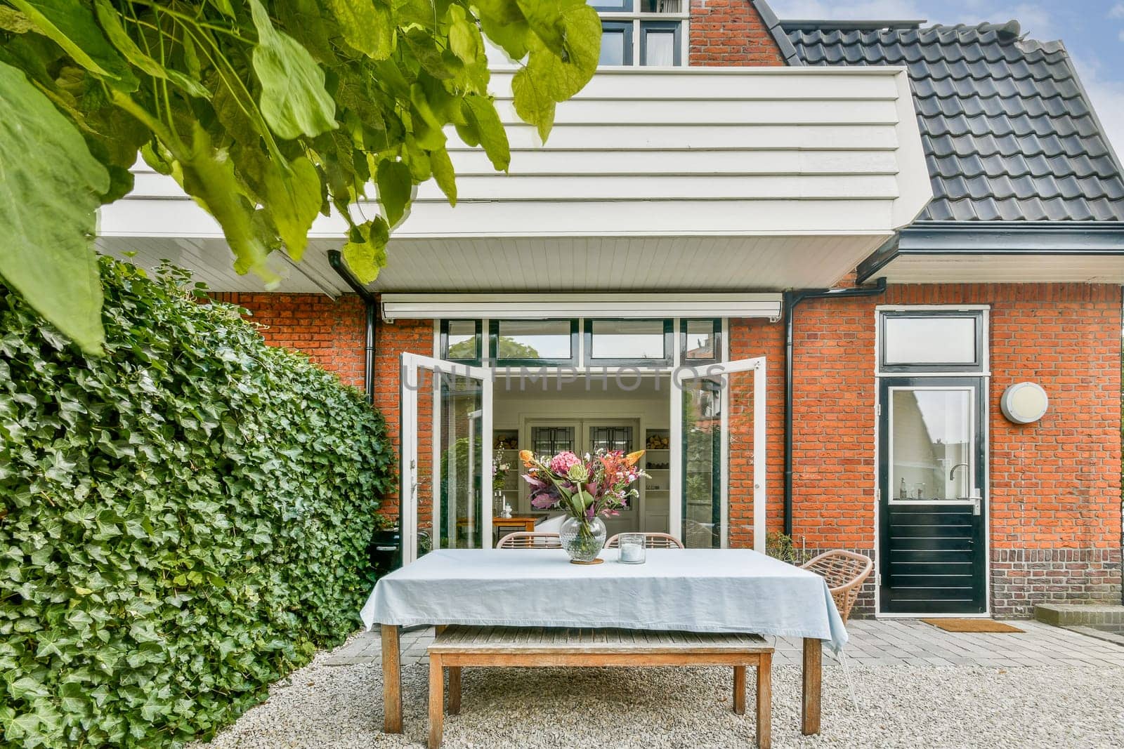 An inviting outdoor dining area featuring a rustic table, floral centerpiece, and lush greenery creating a tranquil atmosphere perfect for gatherings.
