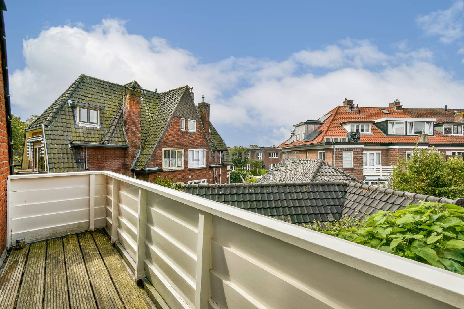 A picturesque view showcasing various styles of residential buildings surrounded by vibrant greenery under a partly cloudy sky.