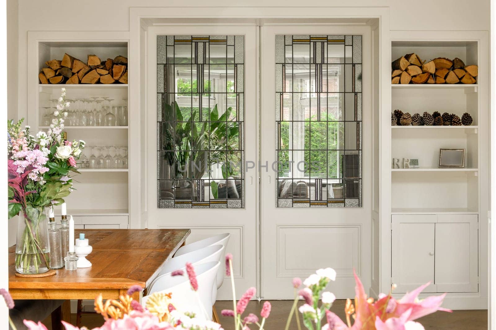 Stylish interior featuring glass paneled doors, organized shelves, and floral arrangements enhancing the overall ambiance and design.