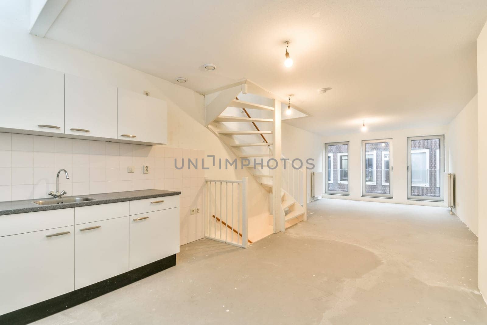 A bright and open layout featuring a modern kitchen with white cabinetry, leading to a spacious living area. Illuminate the space with natural light.