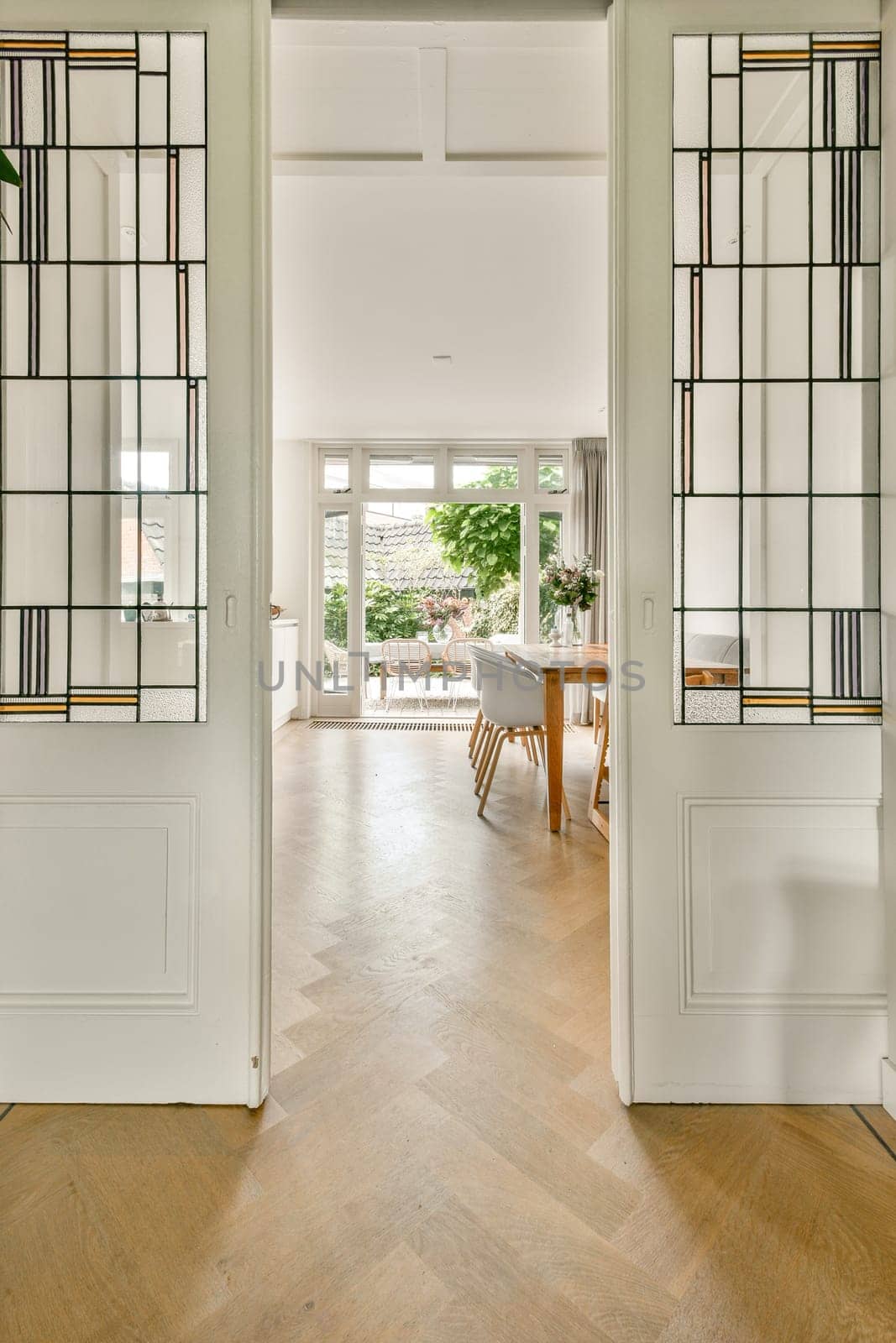 A beautifully designed modern interior featuring an open doorway that invites natural light. The warm wooden flooring complements elegant decor.