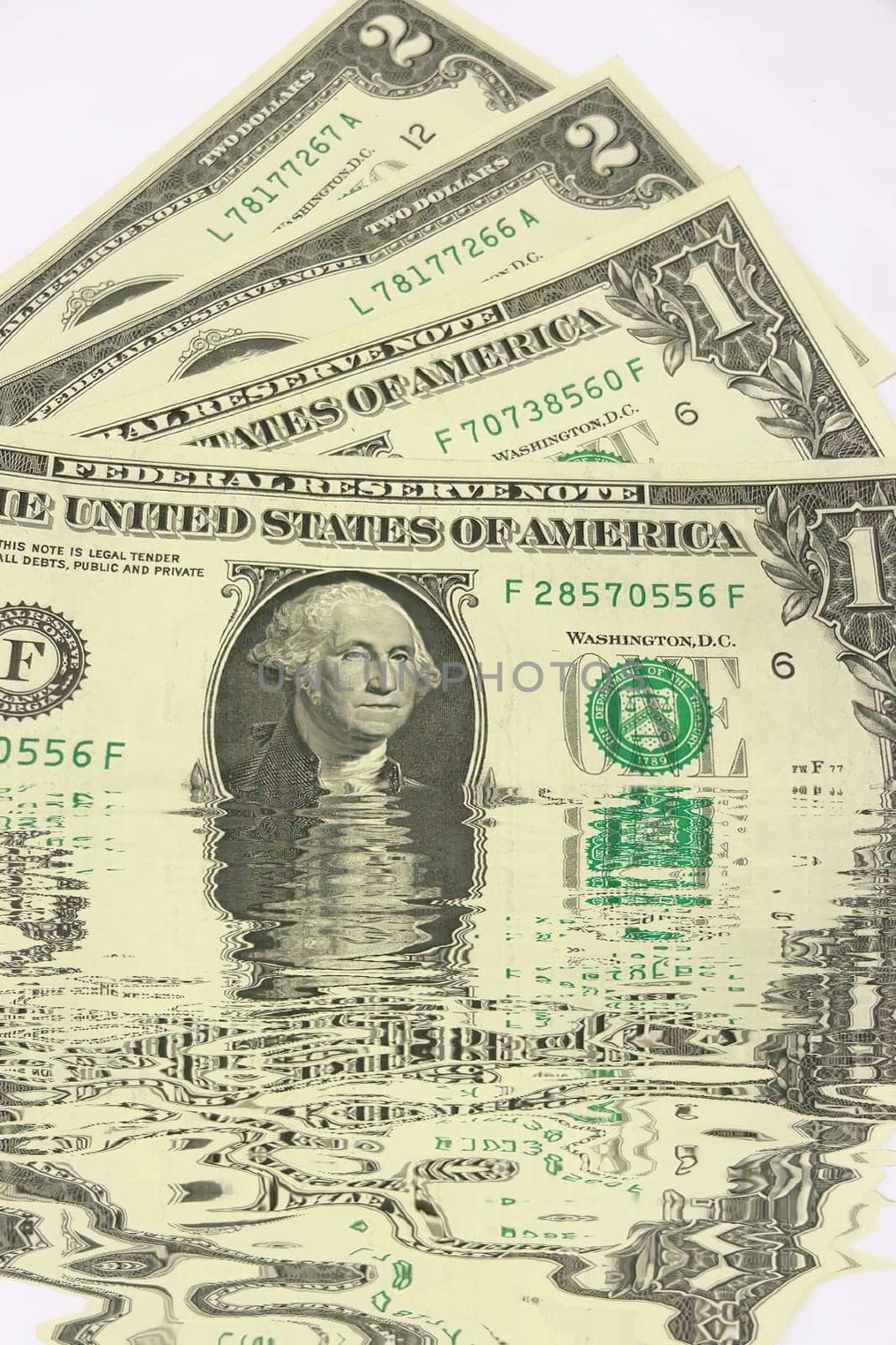Creative conceptual image of US dollar bills partially submerged in water with a water reflection effect. Symbolizes financial crisis, liquidity problems, or a fluctuating economy. Ideal for articles or graphics related to money, finance, economics, or global markets.