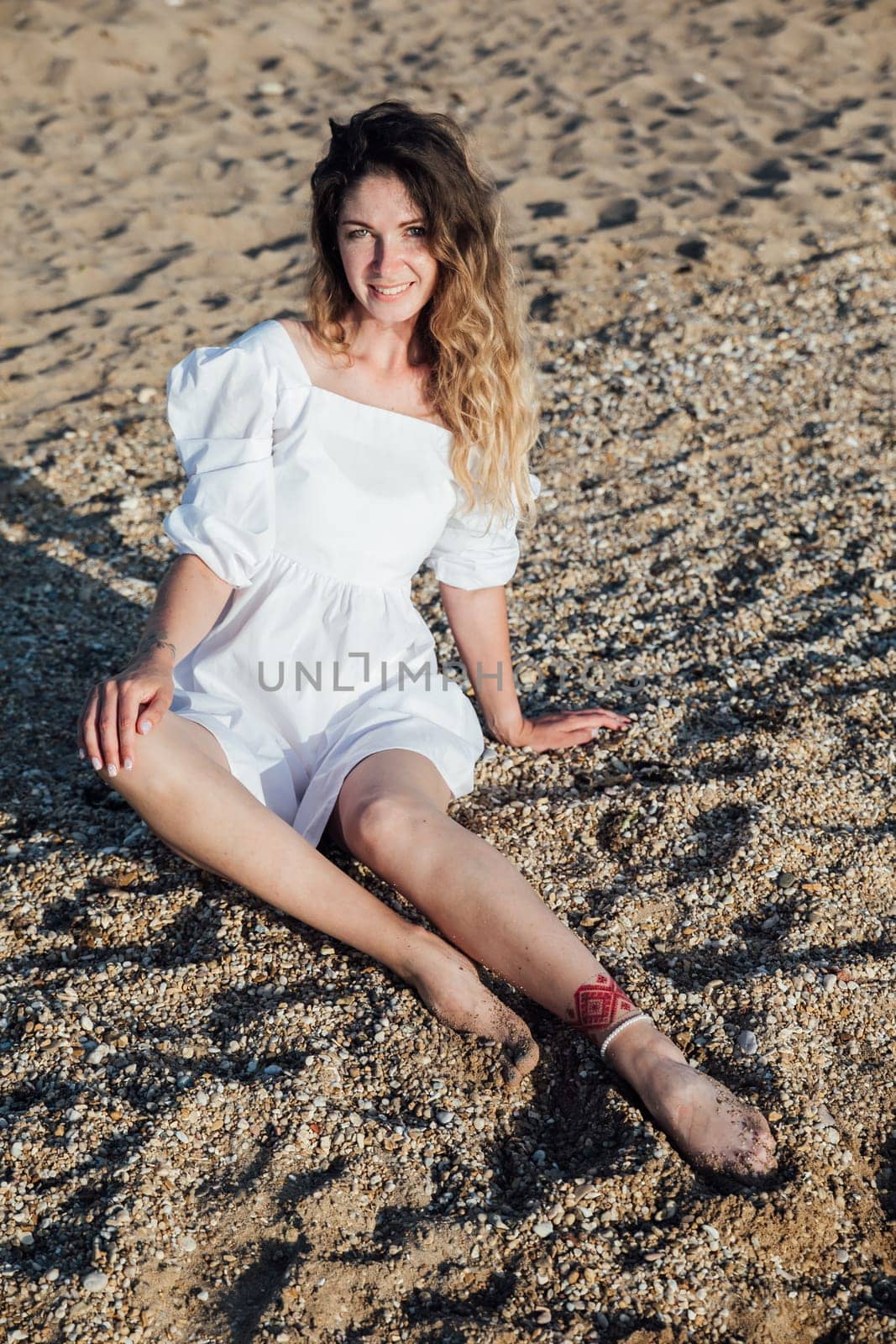 Portrait of a beautiful woman in a light summer dress on a walk on the beach by the sea
