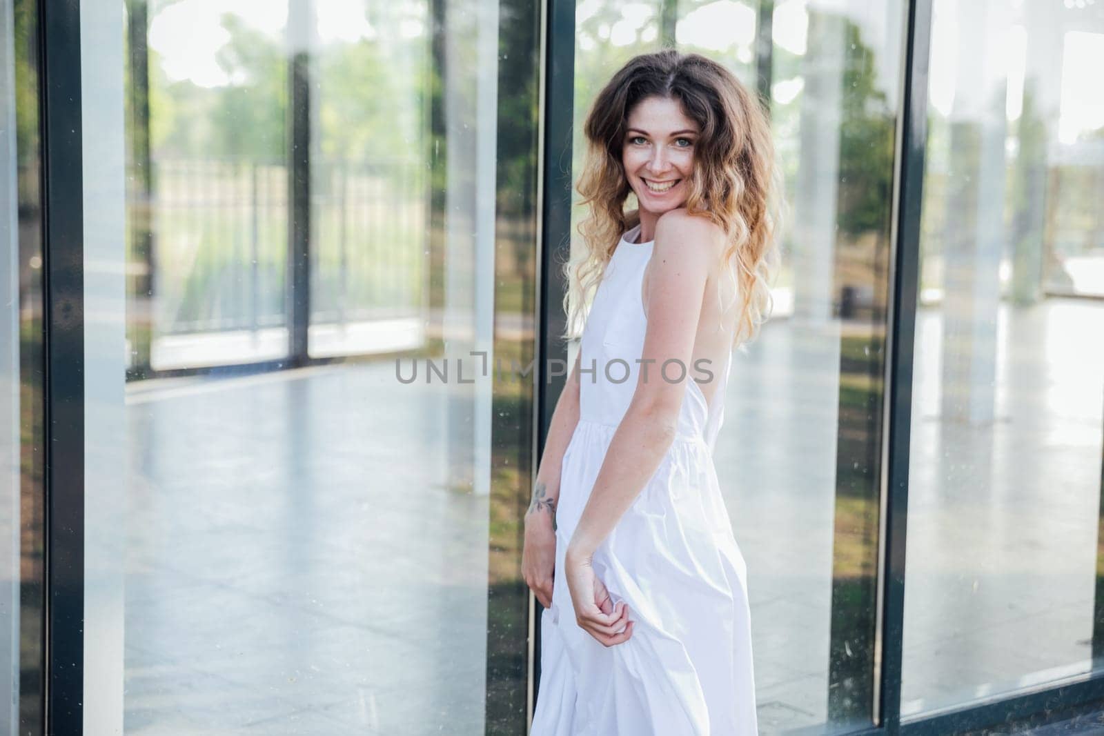 Portrait of a woman smiling in a light summer dress in the park on a walk