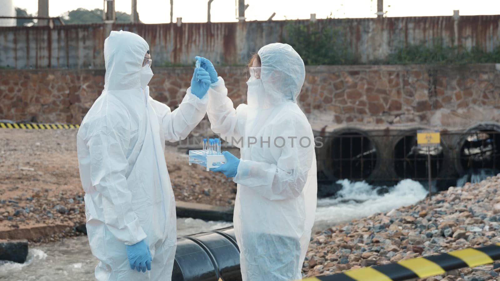 Ecologist sampling water from the river with test tube, Scientist or Biologist in a protective suit and protect mask collects sample of waste water from industrial for analyze, problem environment