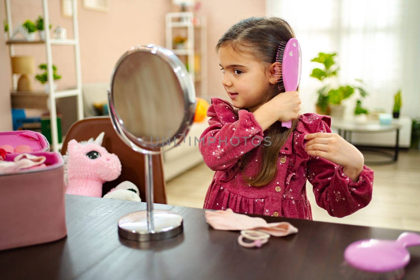 In a bright and inviting room, a young girl brushes her hair with a focused expression, surrounded by soft toys and vibrant decor. Her joyful moment reflects a playful spirit of childhood.