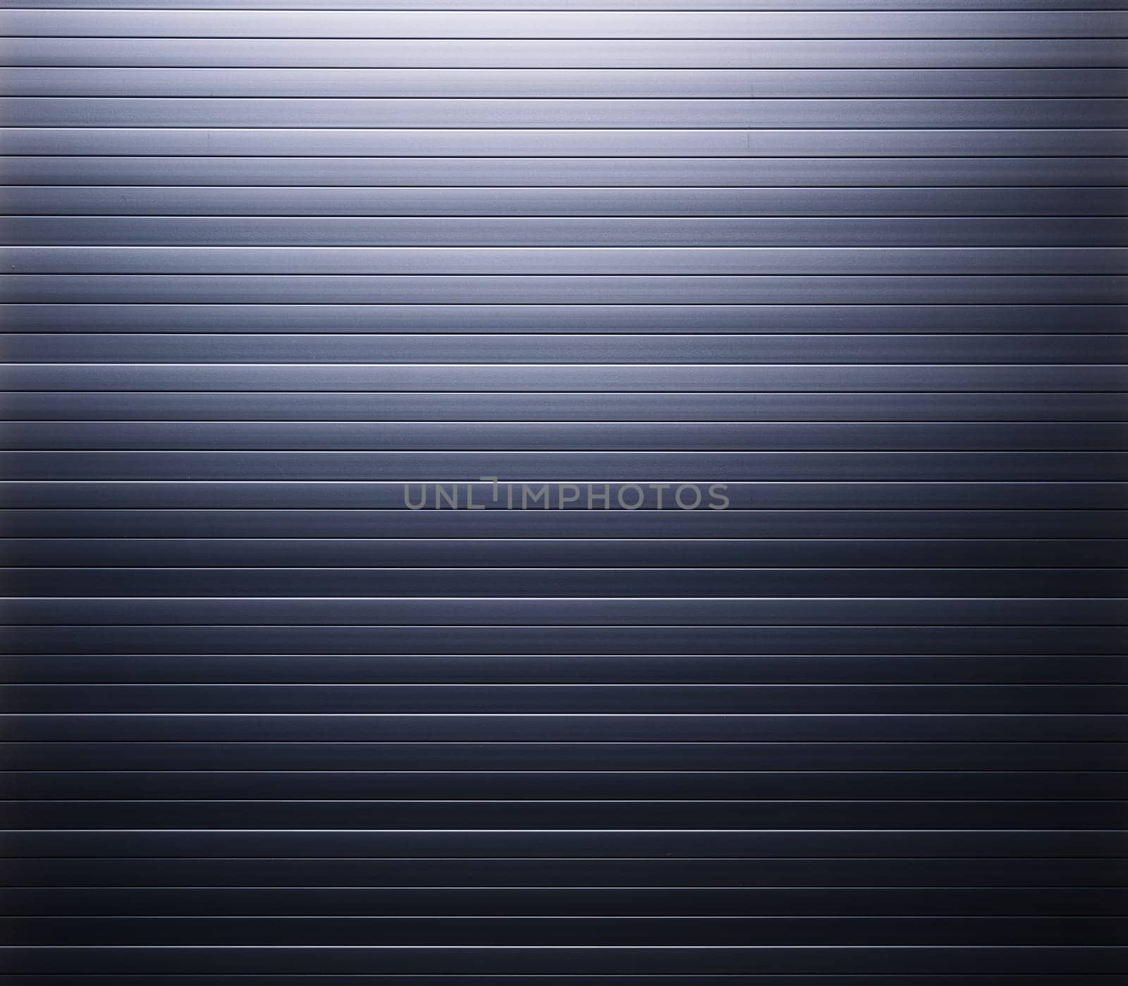Gradient lighting is giving a dramatic look to corrugated metal, ideal as industrial background