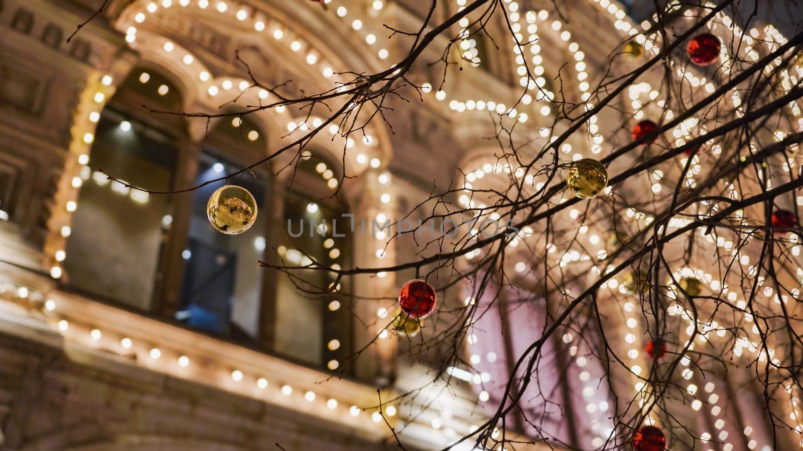 Glowing christmas lights and colorful baubles decorating a building facade during festive season