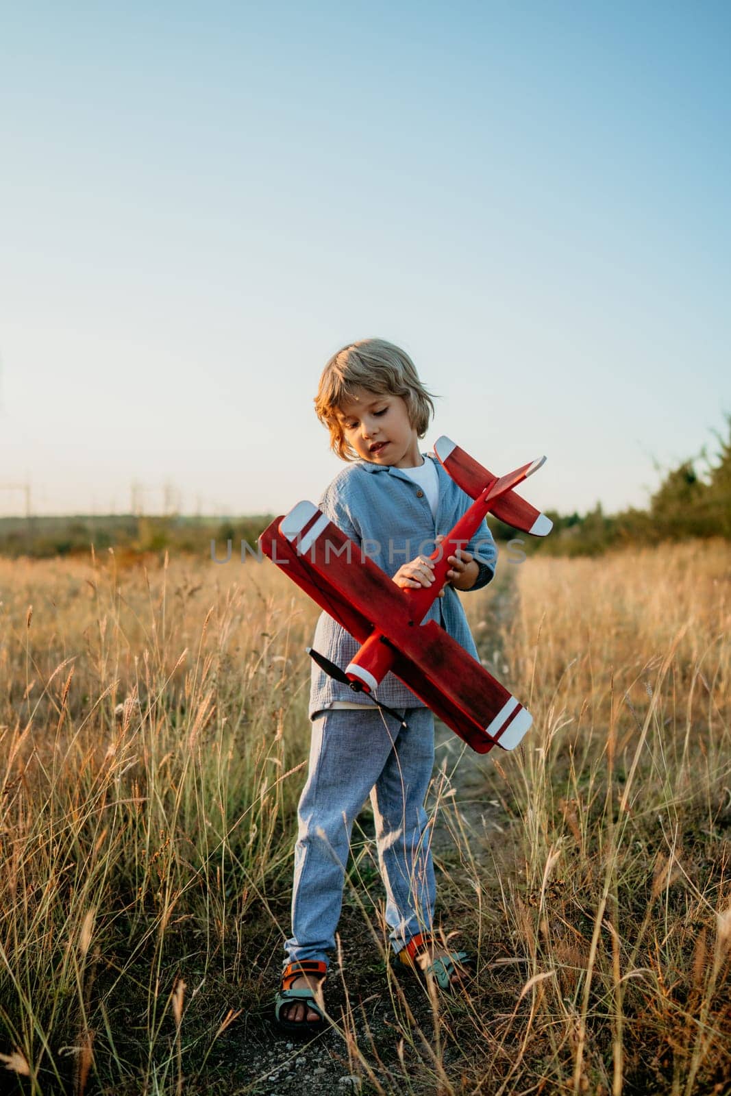 Smiling curious 5 years old preschool child boy plays with craft wooden retro styled airplane toy, discovering future profession interest, dreamer kid flying, traveling. High quality photo