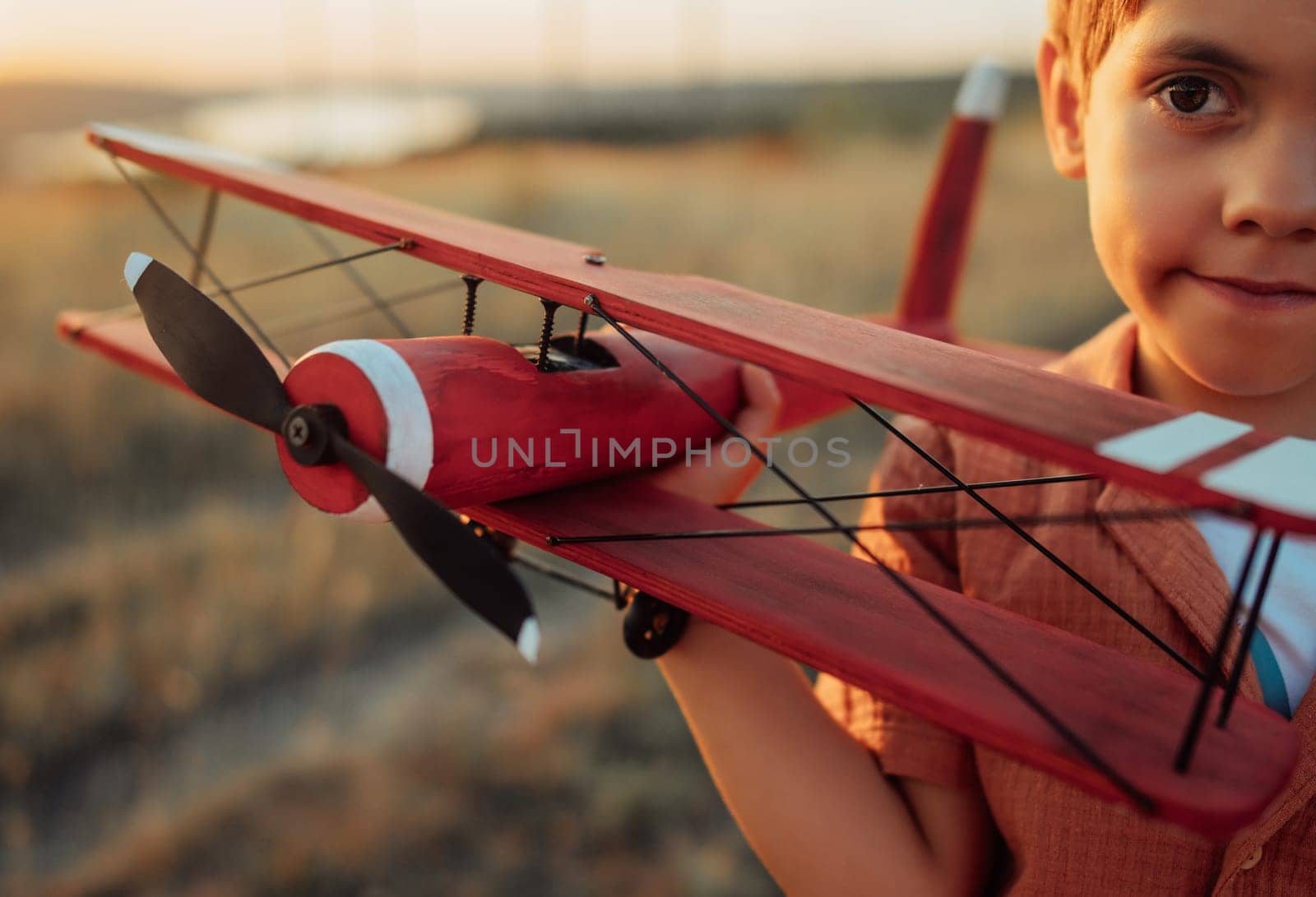 Smiling curious 5 years old preschool child boy plays with craft wooden retro styled airplane toy, discovering future profession interest, dreamer kid flying, traveling. High quality photo