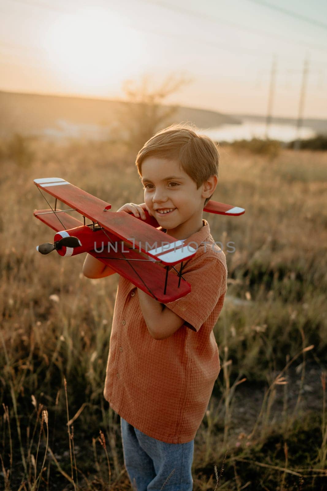 Smiling curious 5 years old preschool child boy plays with craft wooden retro styled airplane toy, discovering future profession interest, dreamer kid flying, traveling. High quality photo