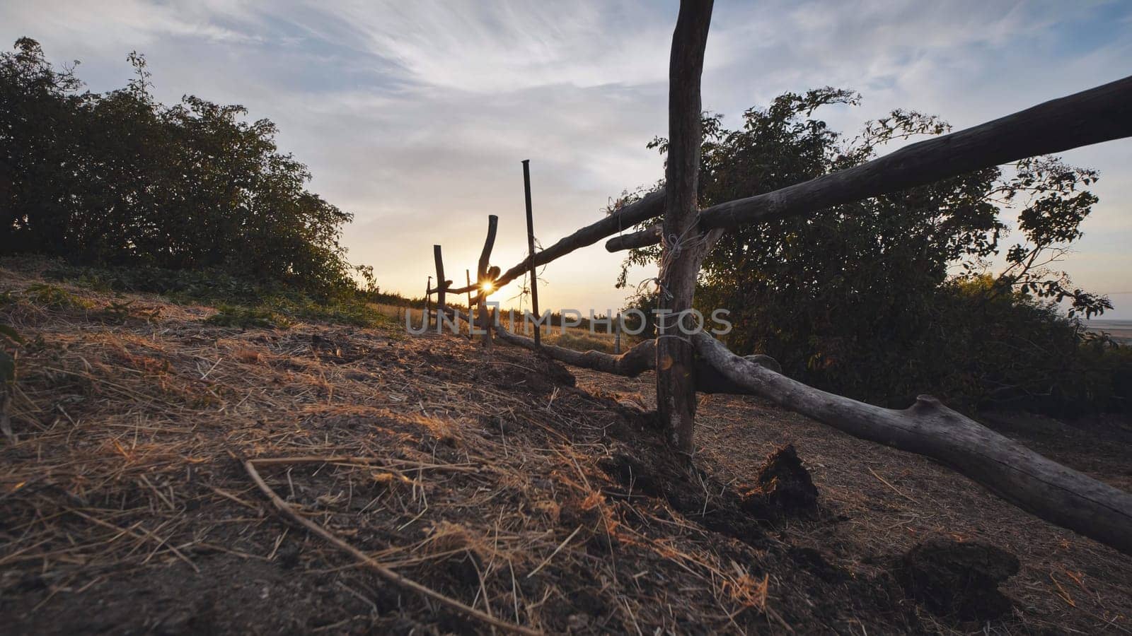 Rustic wooden fence dividing fields in the countryside, creating a picturesque scene at sunset