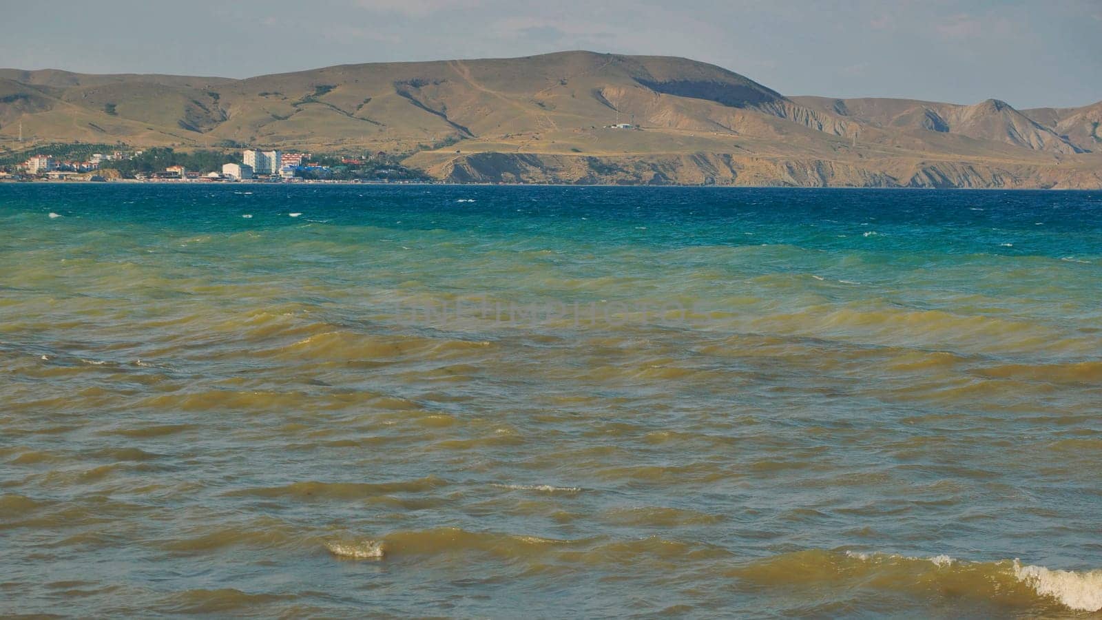 Small waves are rolling on the Black Sea near Koktebel, Crimea, with the extinct volcano Kara Dag in the background