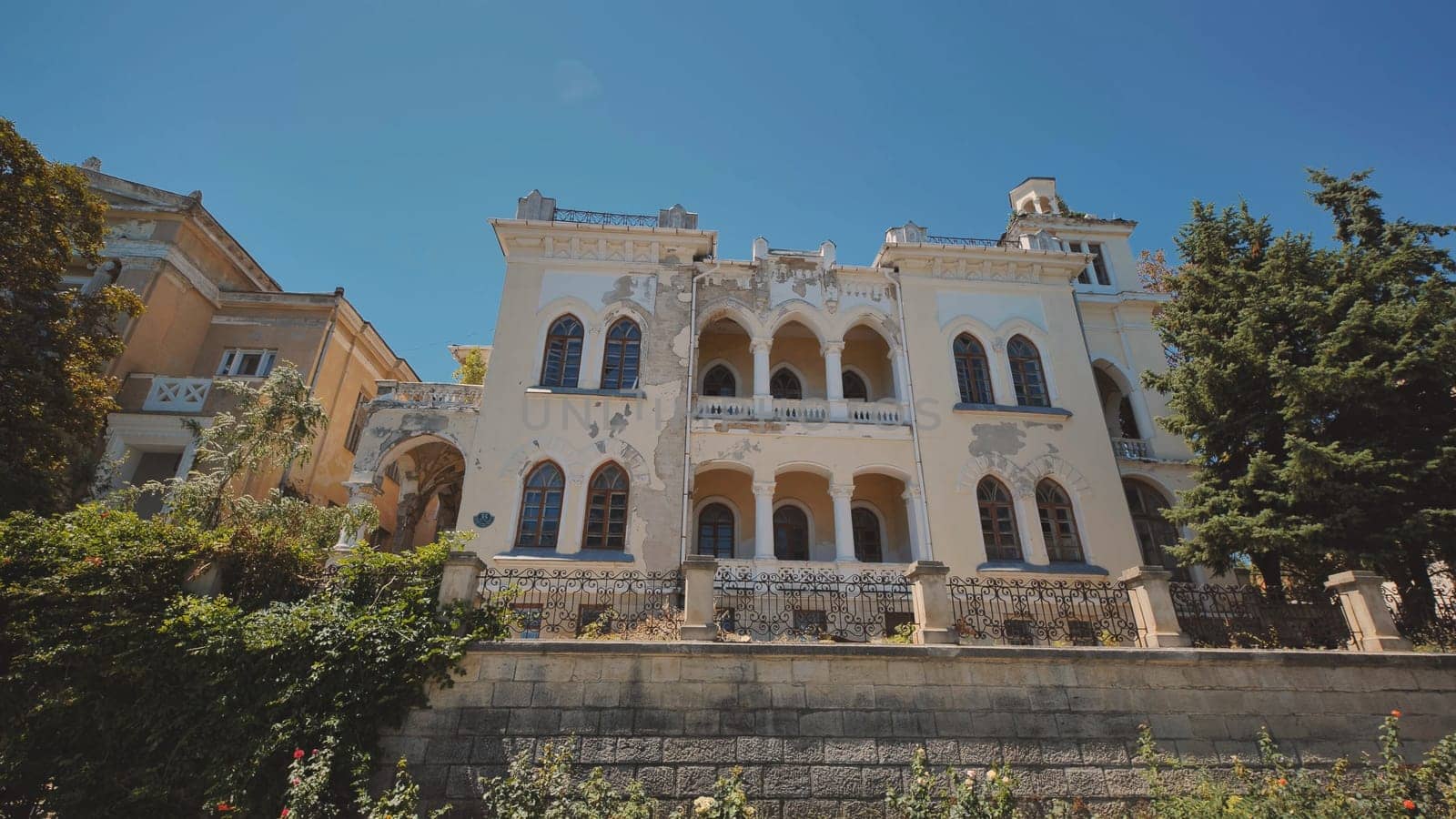 Old abandoned mansion in Crimea peninsula with decaying facade and overgrown vegetation, showing signs of neglect and disrepair